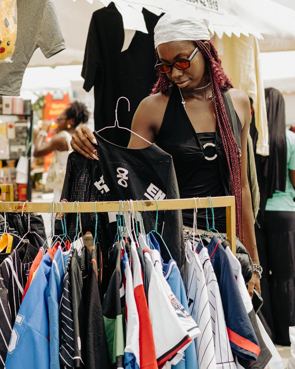 A shopper checking a rail of secondhand clothing at the market